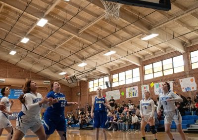 A photograph of an active WSBC basketball game in the ASDB gymnasium. On court are the competing Utah Eagle and Arizona Sentinel girls teams. In the photo, an Eagle player has just released a shot attempt from the high post.