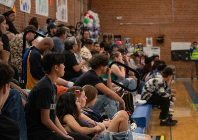 A photograph of a large crowd watching an active WSBC basketball game in the ASDB gymnasium. Nearly every person in the crowd is looking towards the left side of the basketball court, which is not pictured within the frame.
