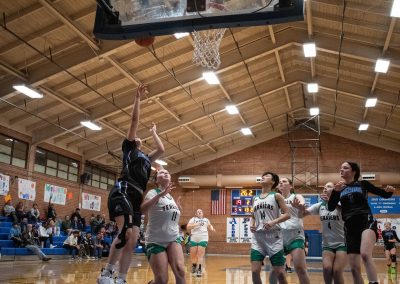 A photograph of an active WSBC basketball game in the ASDB gymnasium. On court are the competing Arizona Sentinel and Washington Terrier girls teams. In the photo, a Sentinel player attempts to score from a layup off the backboard.