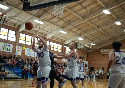 A photograph of an active WSBC basketball game in the ASDB gymnasium. On court are the competing Arizona Sentinel and Oregon Panther boys teams. In the photo, the basketball is pictured flying out of bounds, directly off the hands of a Panther player.
