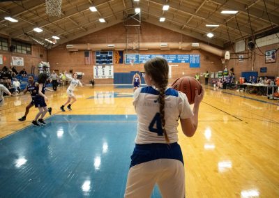 A photograph of an active WSBC basketball game in the ASDB gymnasium. On court are the competing Oregon Panther and Arizona Sentinel girls teams. In the photo, an out of bounds Sentinel player looks to inbound the basketball to an open teammate.