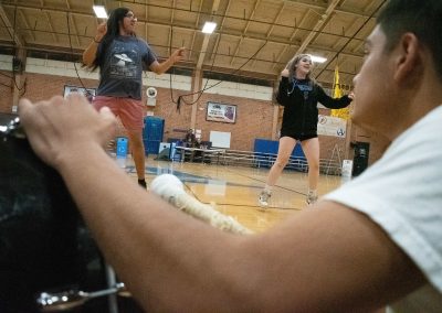 An over-the-shoulder photograph of two students dancing in the ASDB gymnasium. In the foreground, a student in a white shirt watches them intently.